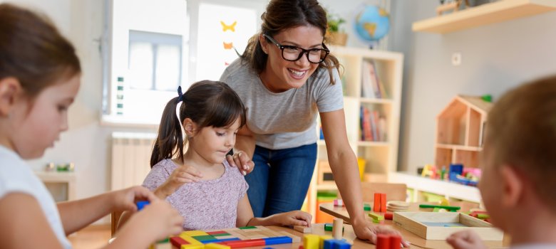 Preschool teacher with children playing with colorful wooden did
