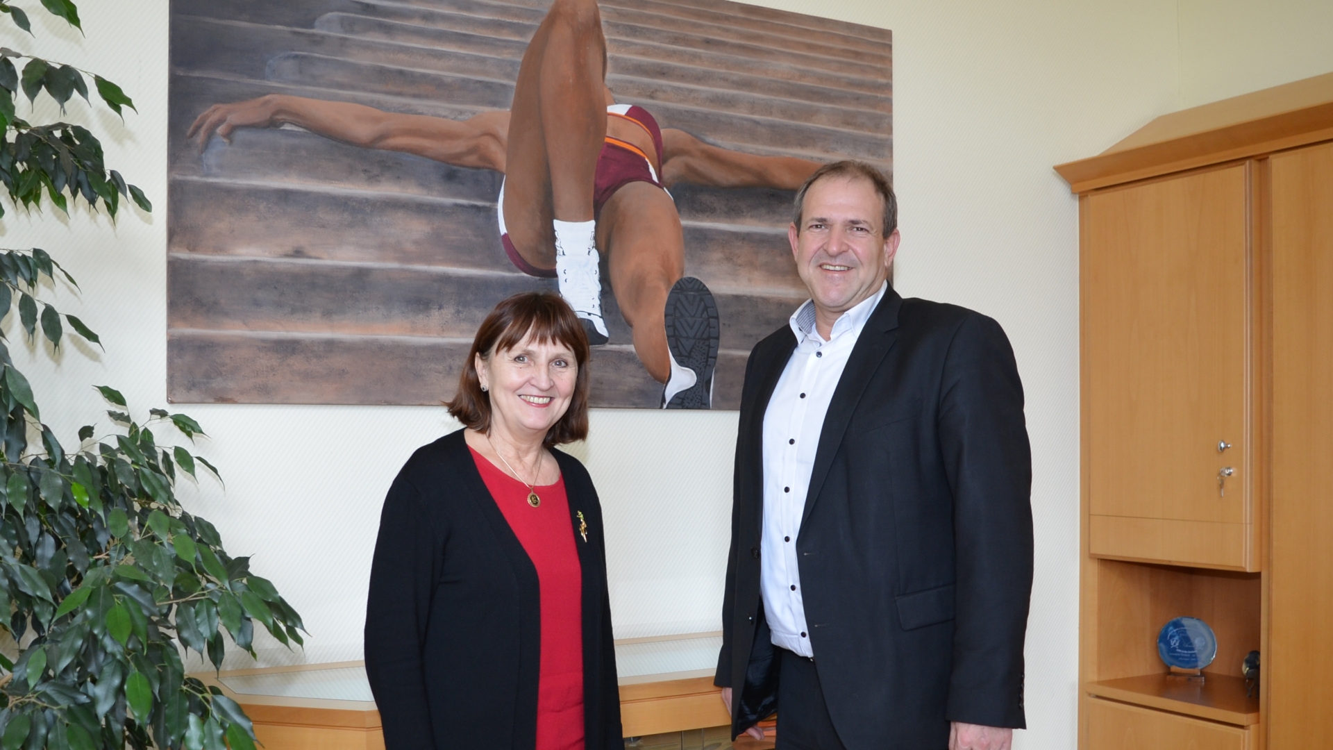 The photo shows the artist Luise Schwarz and Lord Mayor Frank Frühauf in front of the painting 'Sportlerin'.