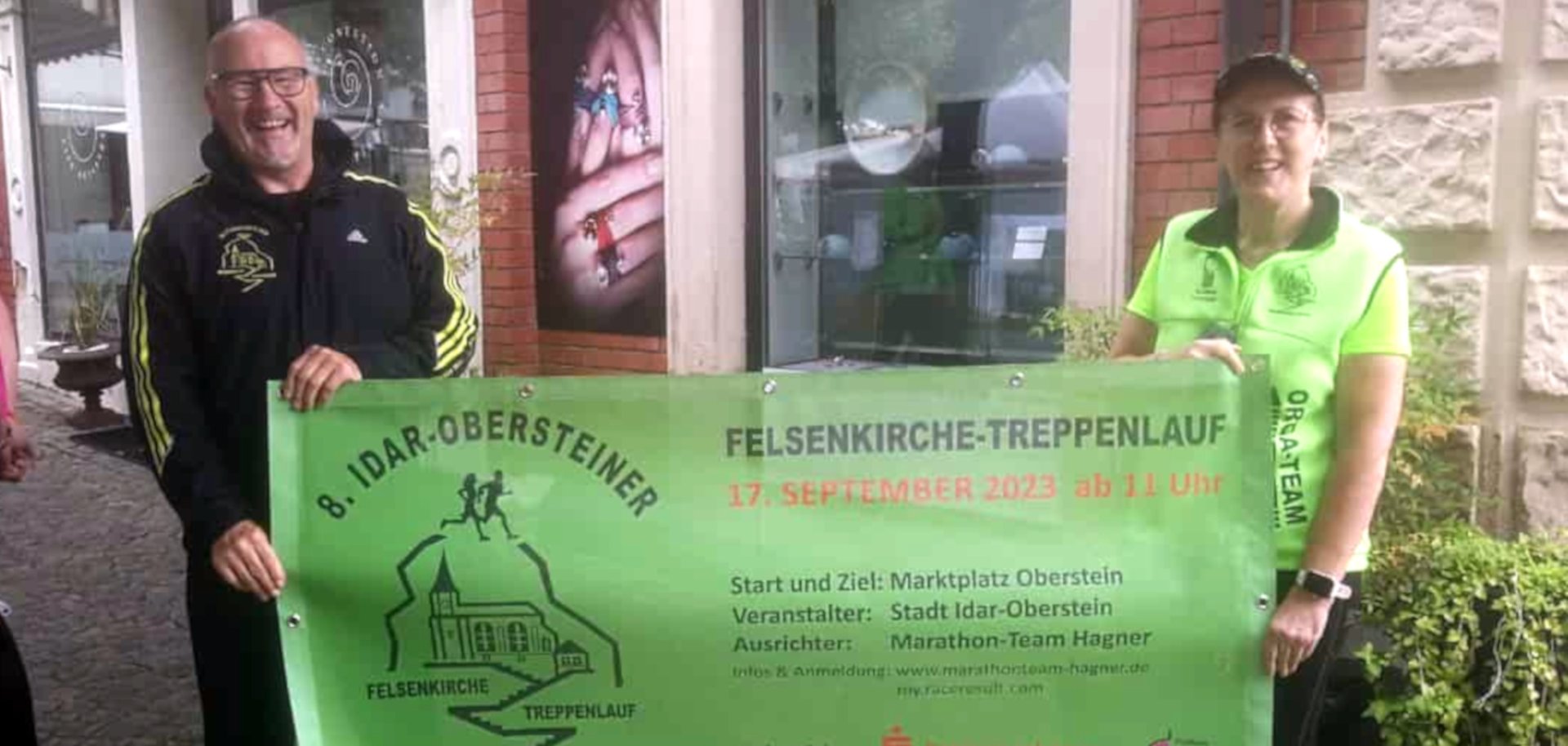 The photo shows the couple Rainer and Ilonka Hagner. They are holding a banner advertising the 8th Idar-Oberstein Rock Church Stair Run.
