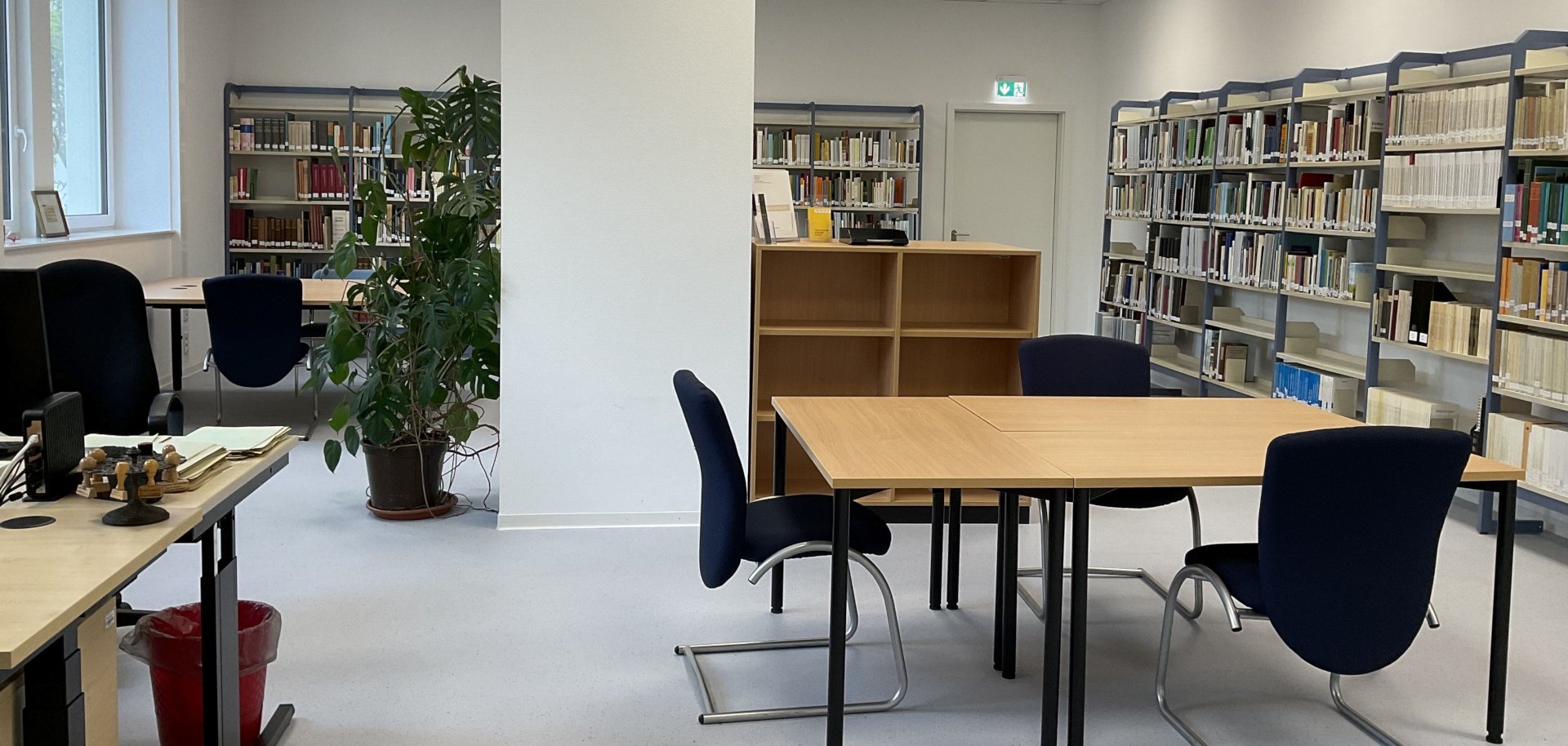 The photo shows the reading room of the city archive with tables, chairs and shelves.