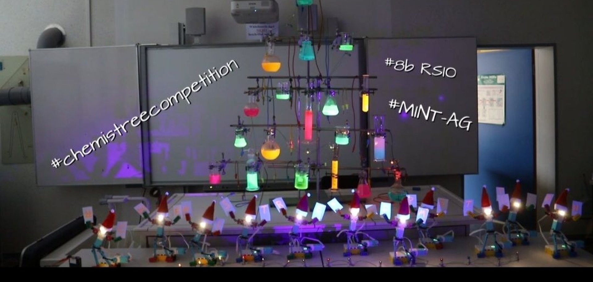 The picture shows the elves standing next to each other on a table, with the "IT tree" behind them.