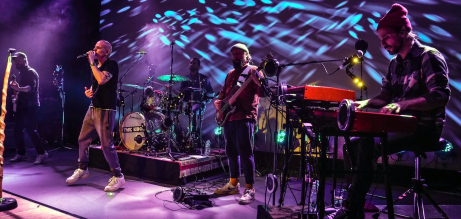 The photo shows Thomas D on stage with the band The KBXS.