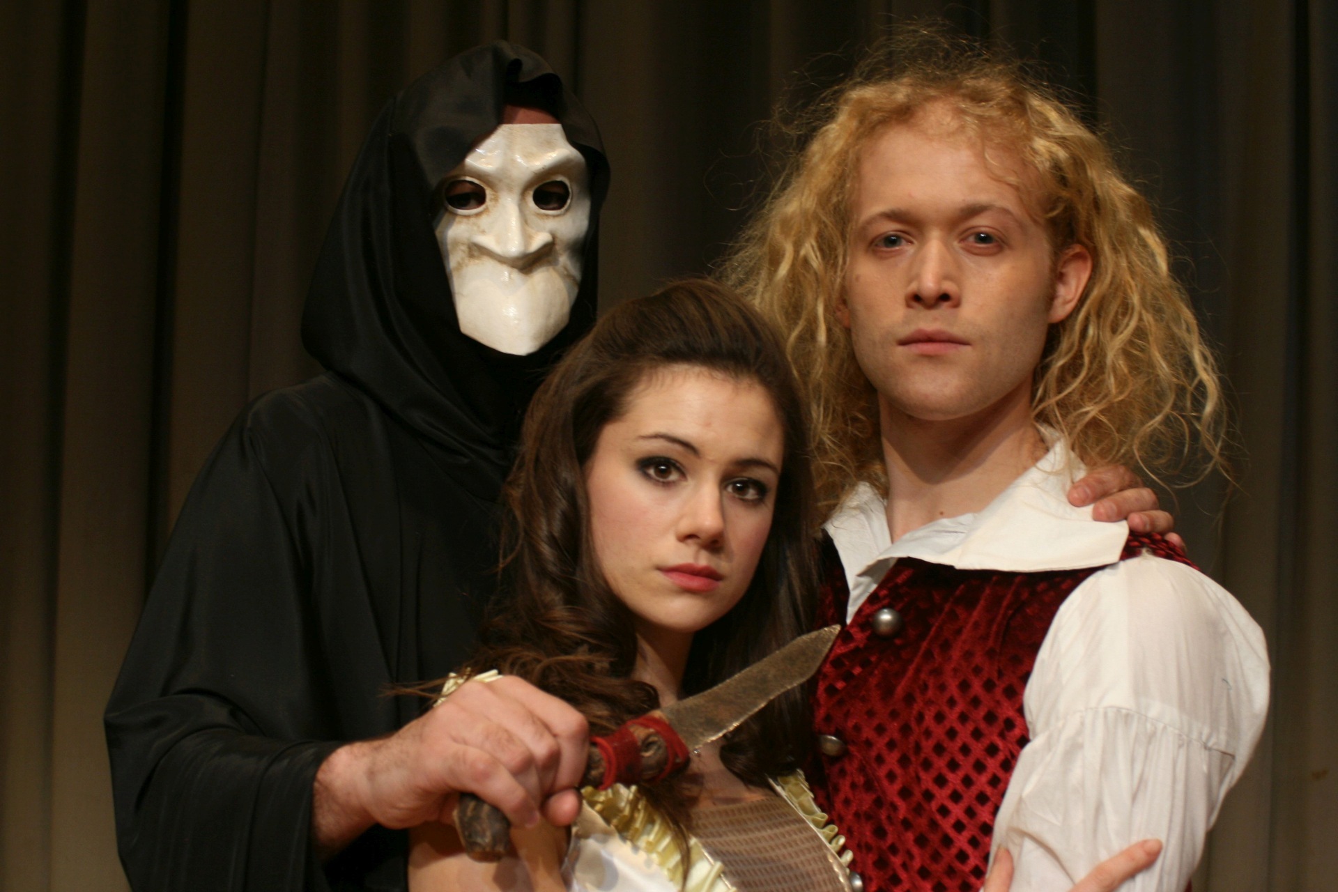 The photo shows the lovers Romeo and Juliet, with Death holding a knife to their throats.