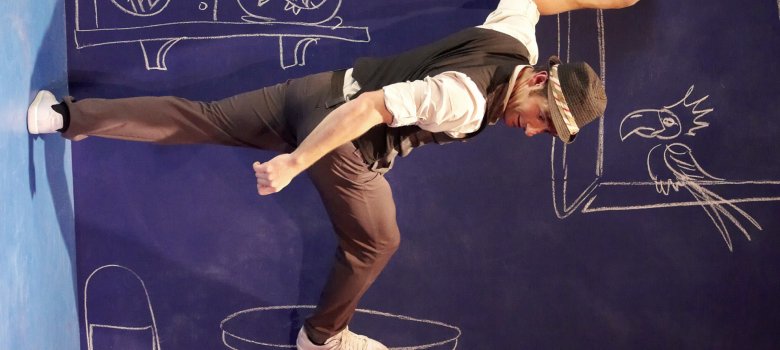 The photo shows the artist, who appears to be walking horizontally along a wall.
