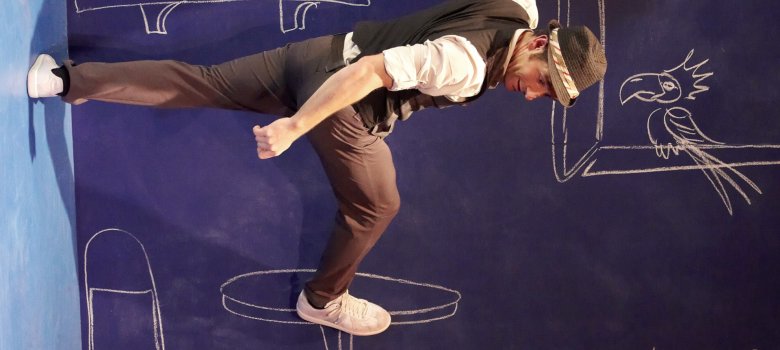 The photo shows the artist, who appears to be walking horizontally along a wall.