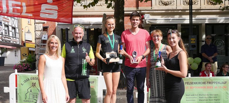 The photo shows the aforementioned people standing next to each other on the winner's podium.
