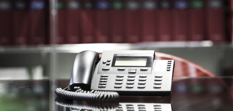 The photo shows a telephone in front of a shelf with files.