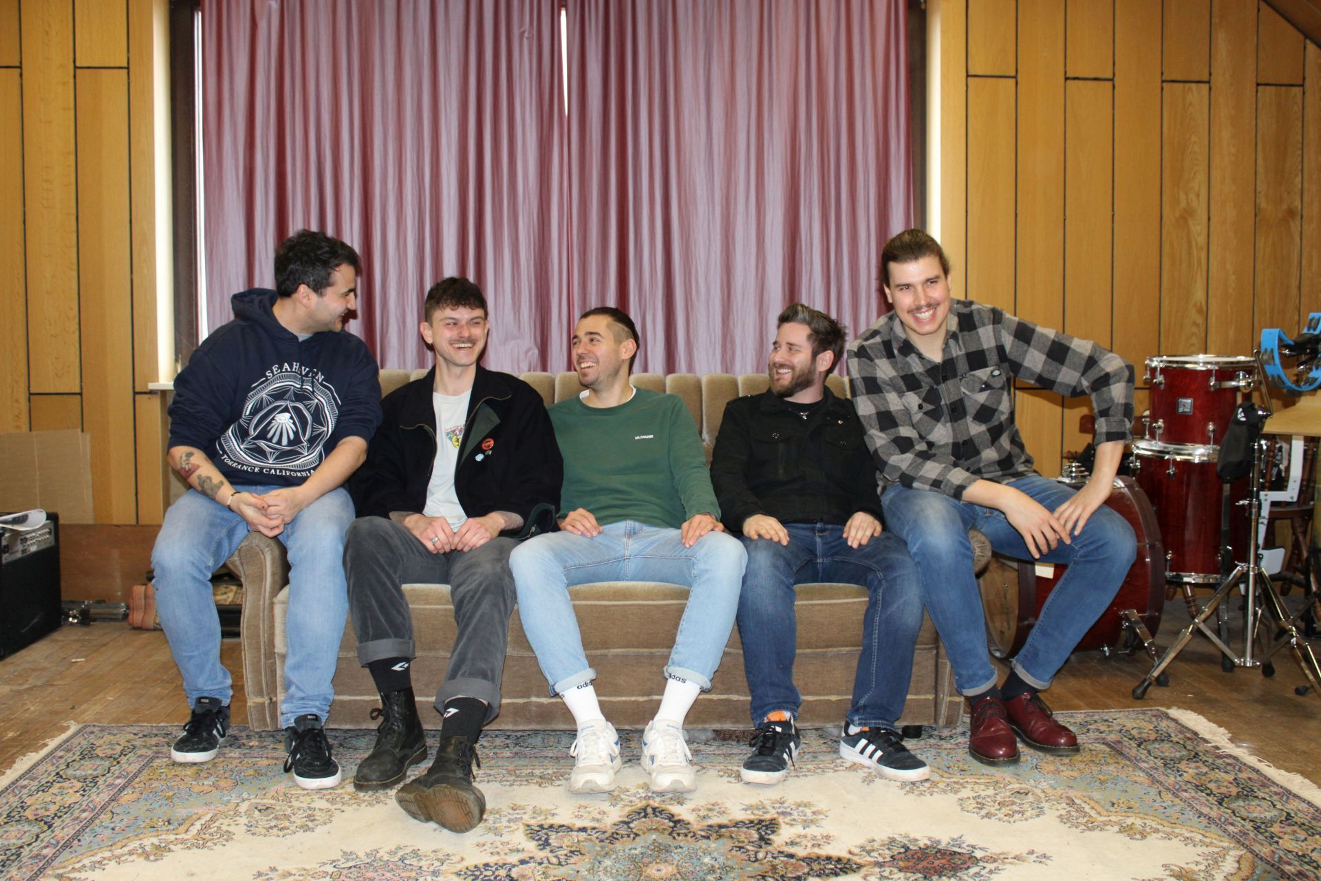 The picture shows the five members of the band summer returns, who are the headliners of the punk rock concert, sitting on a couch.