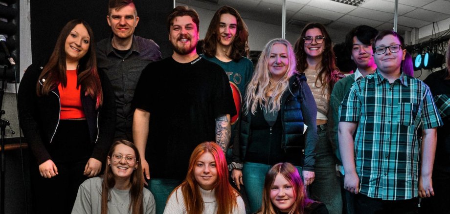 The photo shows the participants and protagonists of the workshop. They are standing on the JAM stage and looking into the camera.