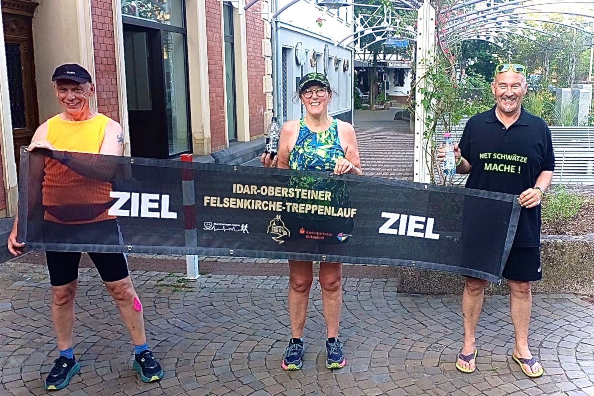 The photo shows the three people standing next to each other on the edge of the market square and holding up the entry banner.