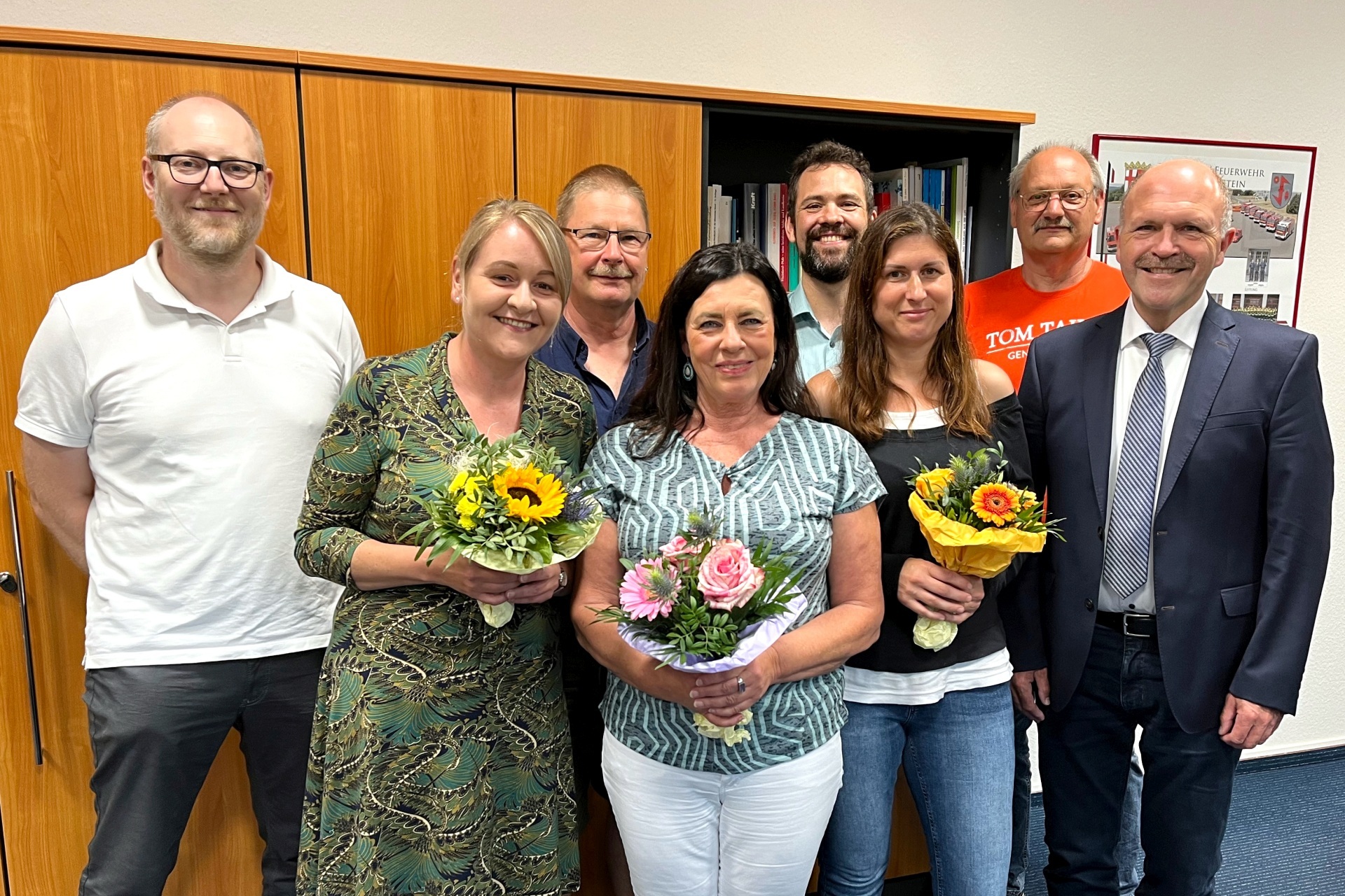The photo shows the three jubilarians, Mayor Marx and four other people. They stand in two rows in front of a wall unit in the mayor's office and look into the camera.