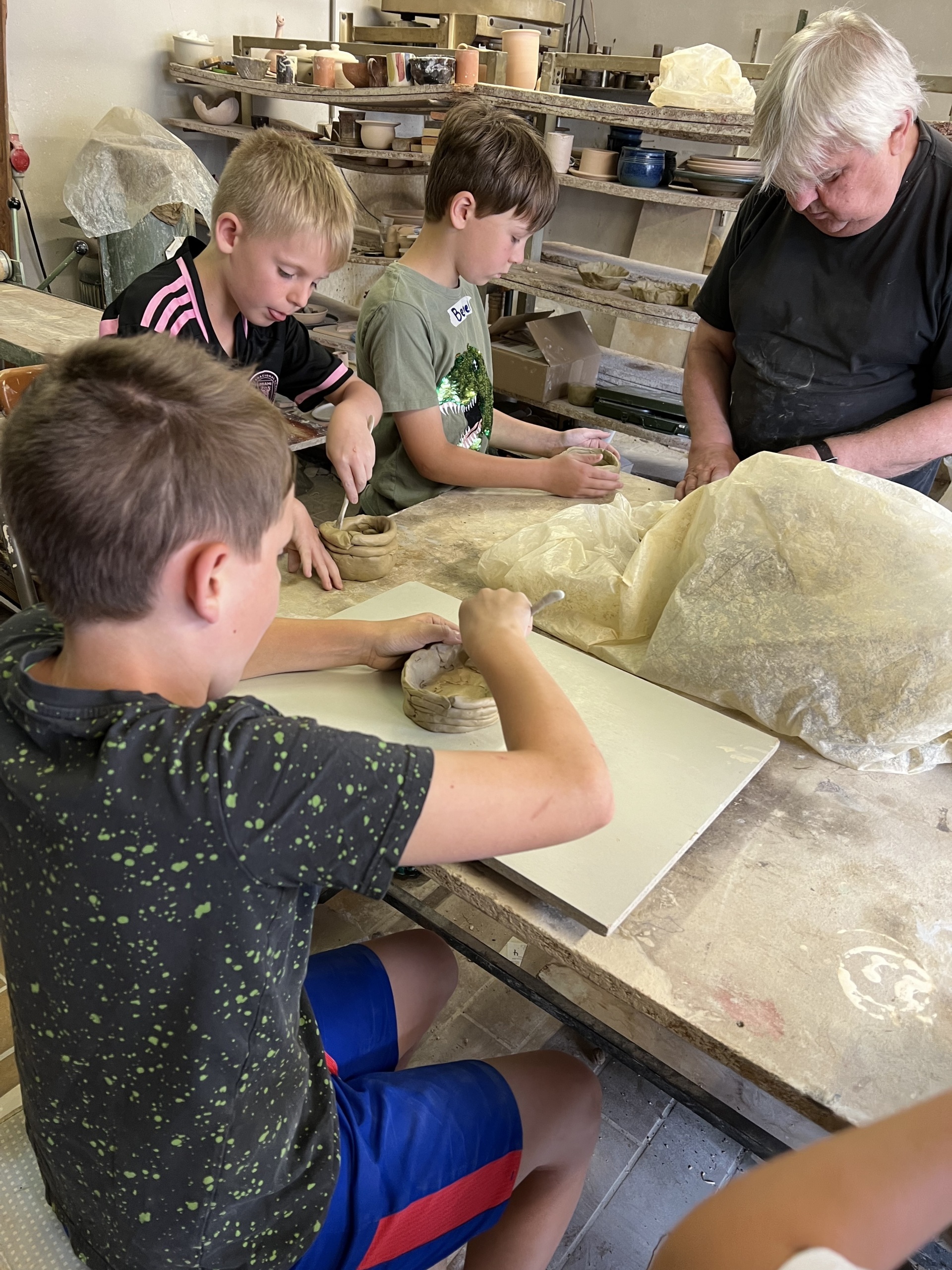 The photo shows the children making pottery together with master potter Manfred Weigel.