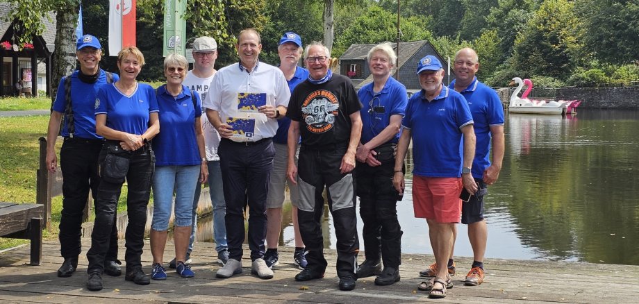 The photo shows the tour participants. Together with Mayor Frühauf, they stand next to each other on a footbridge at the Kallwiesweiher pond and look into the camera.