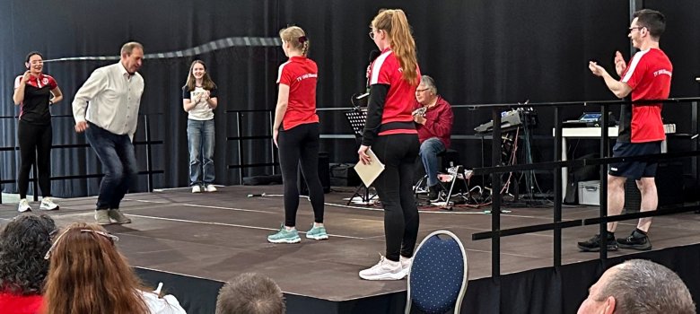 The photo shows the stage. The rope skippers from TV Oberstein are standing on it. Mayor Frank Frühauf jumps over a rope that two rope skippers are skipping.