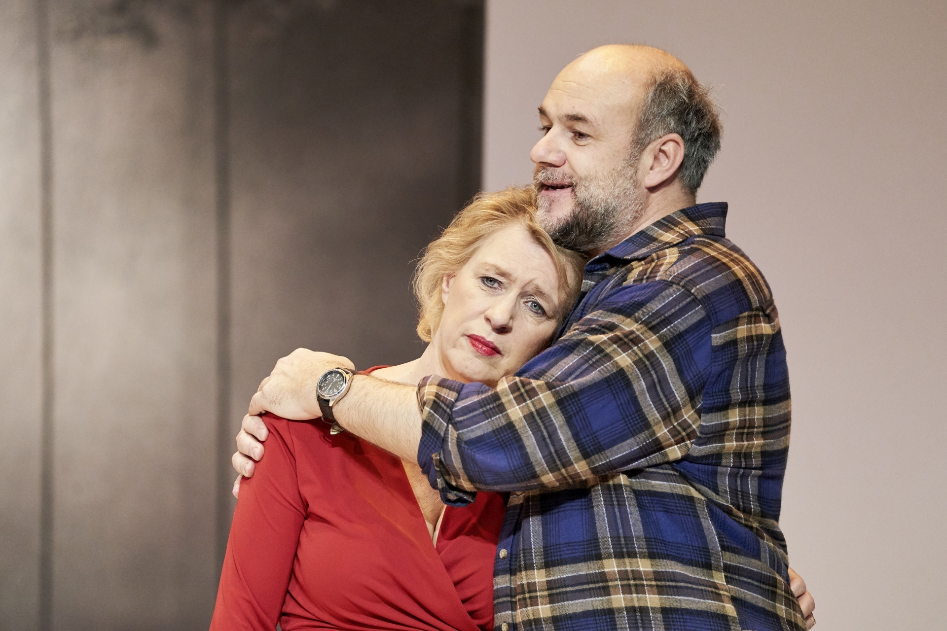 The photo shows a couple on stage. The woman is leaning on the chest of the man who is embracing her.