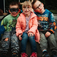 The photo shows three children wearing make-up.
