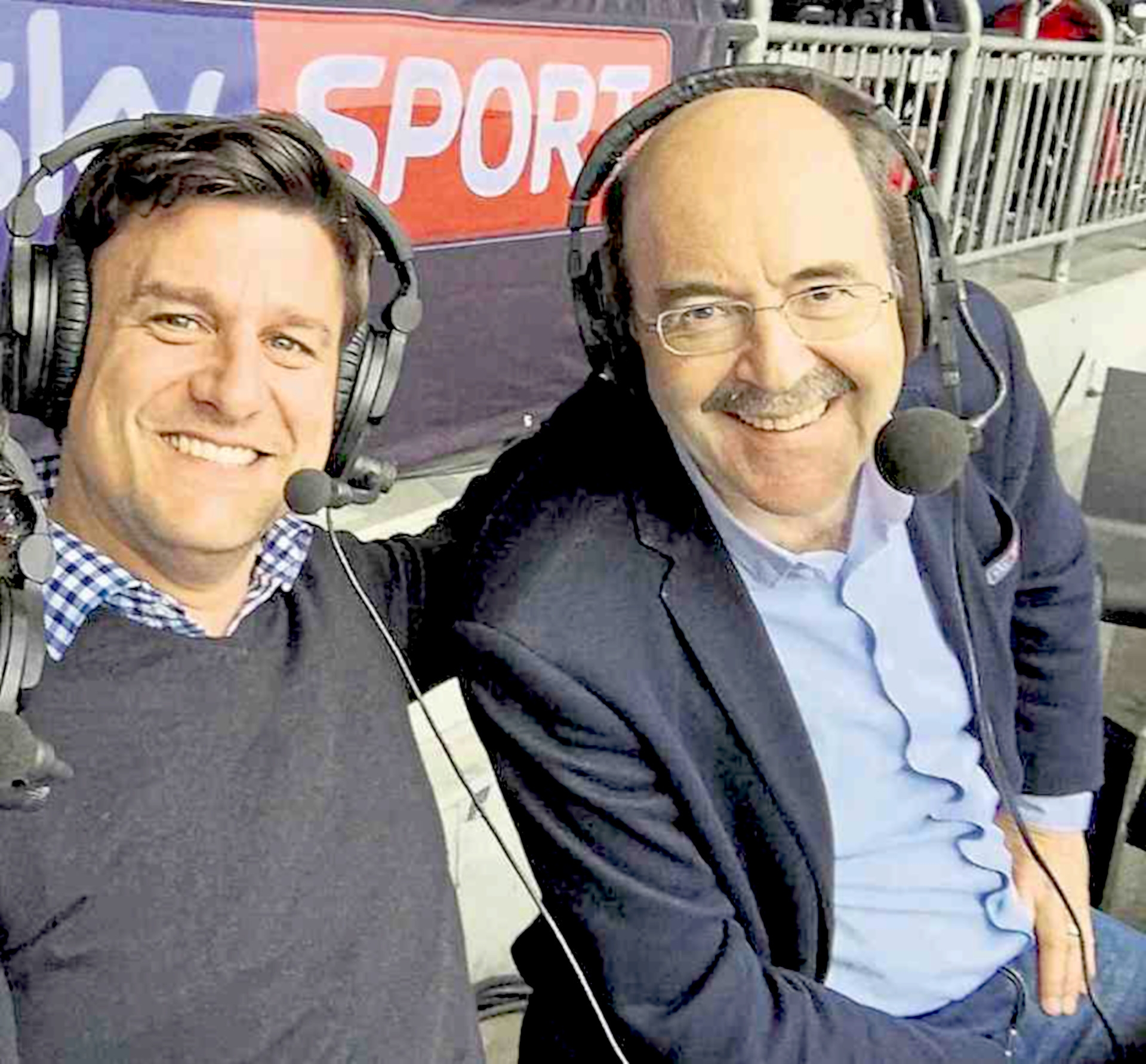 The photo shows the two people. They are sitting next to each other and have headphones with speaker microphones on their heads.