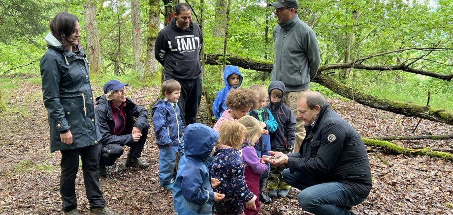 The picture shows Lord Mayor Frank Frühauf handing over small gemstones to the children of the forest daycare center.