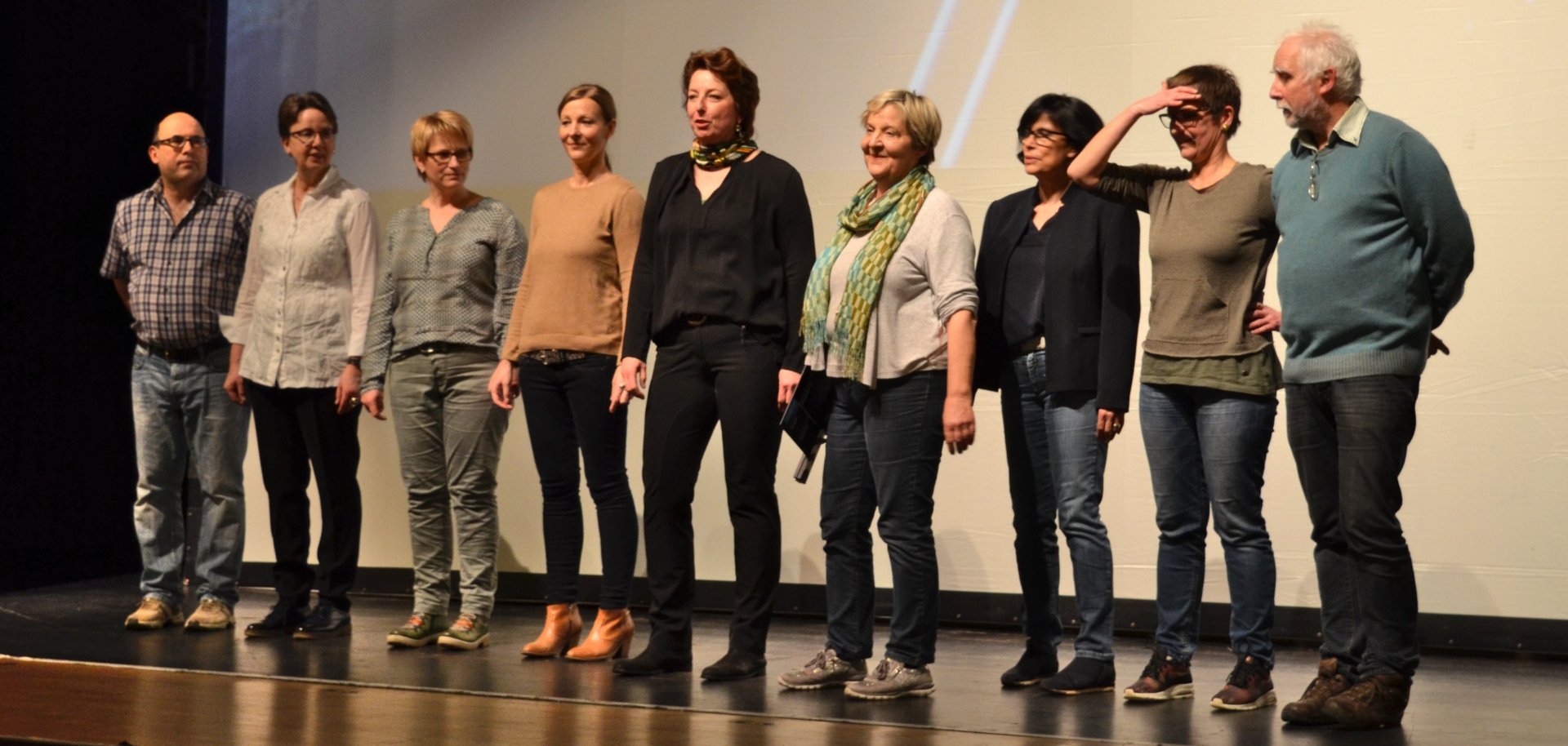 The photo shows nine members of the initiative. They stand next to each other on the stage of the Stadttheater and look into the theater hall.