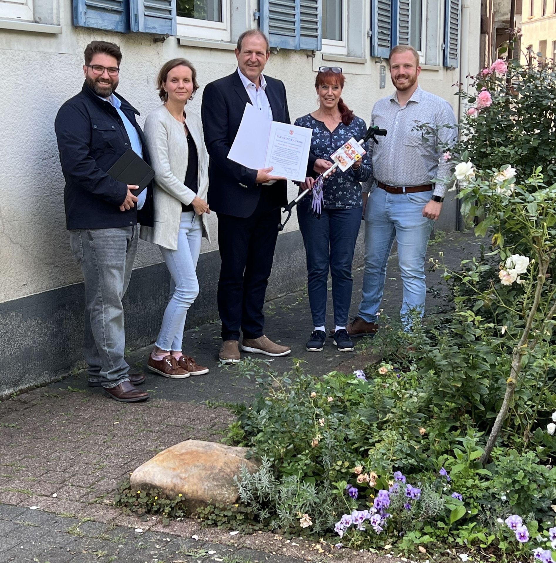 The photo shows the people present in front of the green space, which is maintained by Elke Grüneberg and her friend.