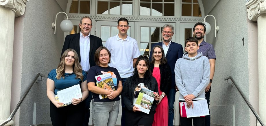The photo shows the people mentioned in the article. They are standing on the steps in front of the town hall and looking into the camera.
