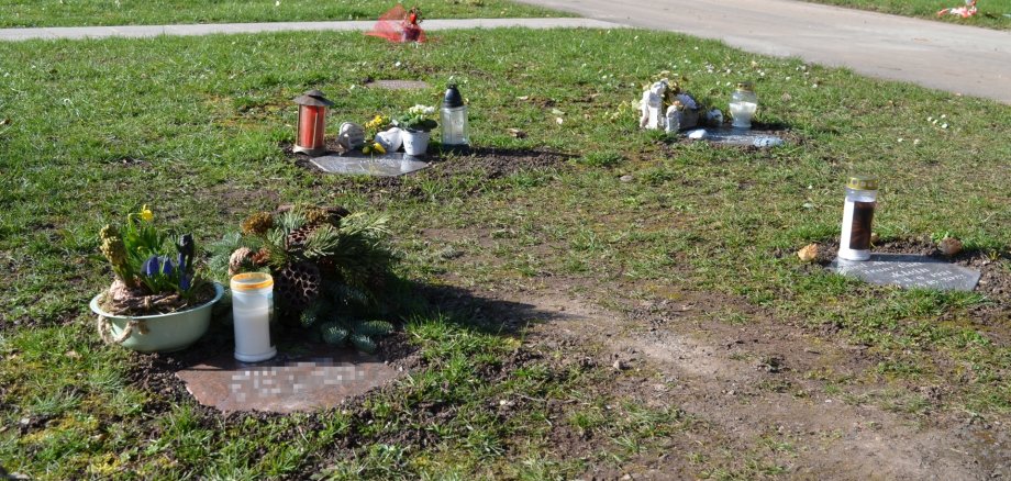The photo shows grave decorations on a burial plot.