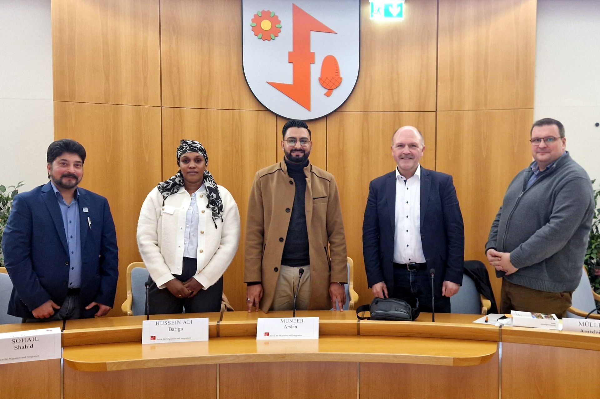 The photo shows the people mentioned. They are standing next to each other in the meeting room and looking into the camera.