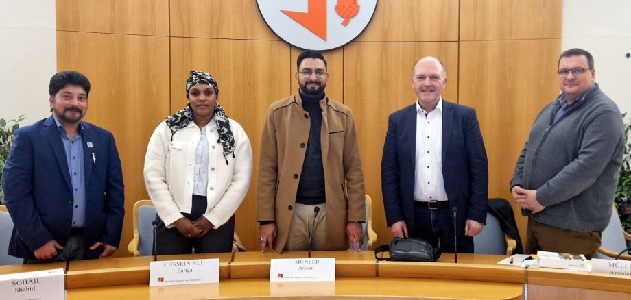 The photo shows the people mentioned. They are standing next to each other in the meeting room and looking into the camera.