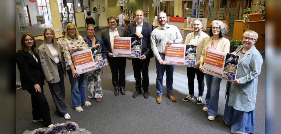 The photo shows the organizers and sponsors standing next to each other in the KSK cashier's hall and holding posters for the event up to the camera.