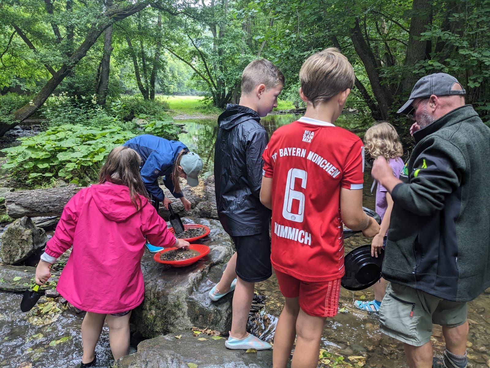 The photo shows children searching for gold in the stream.