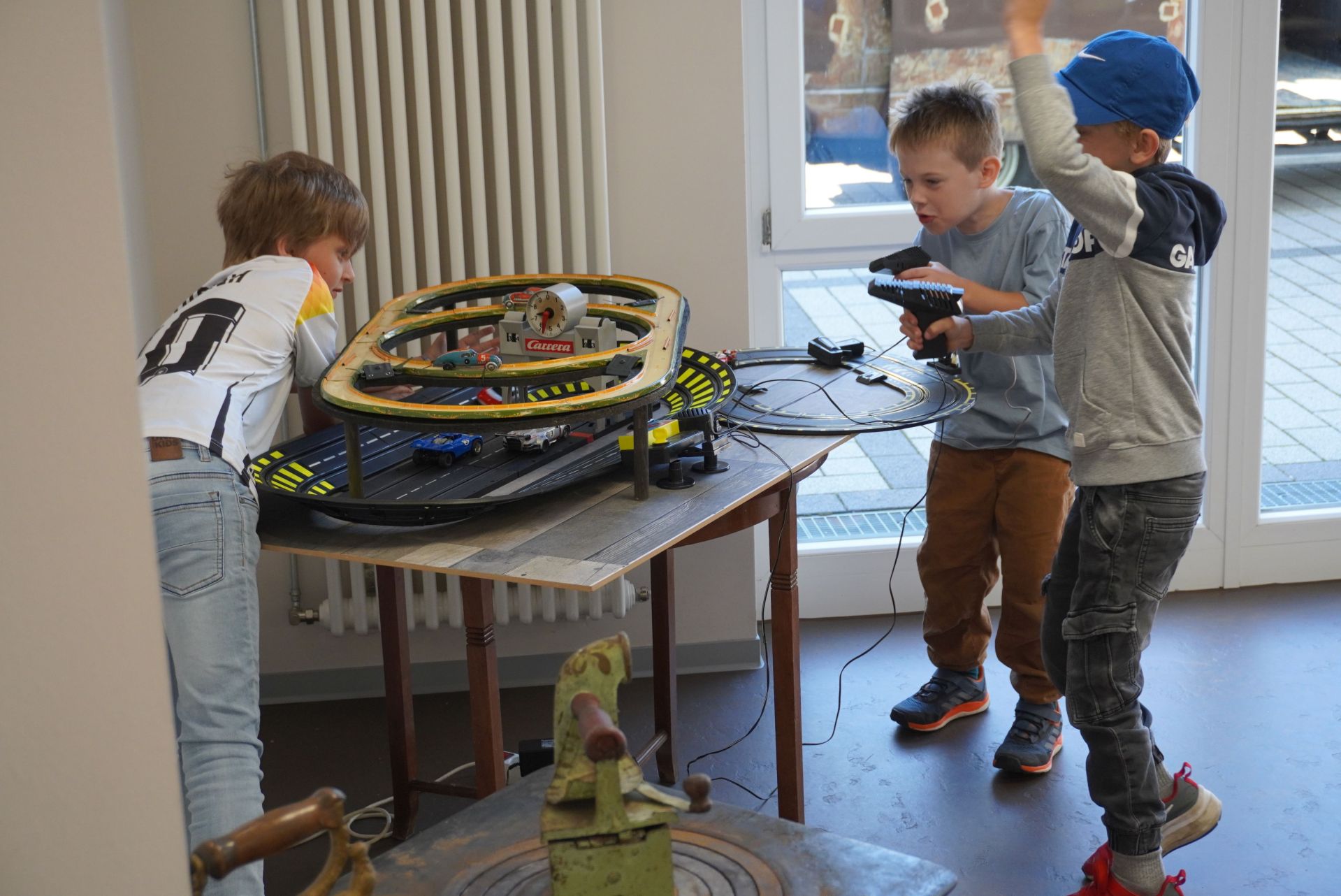 The photo shows three children playing with a Carrera track.