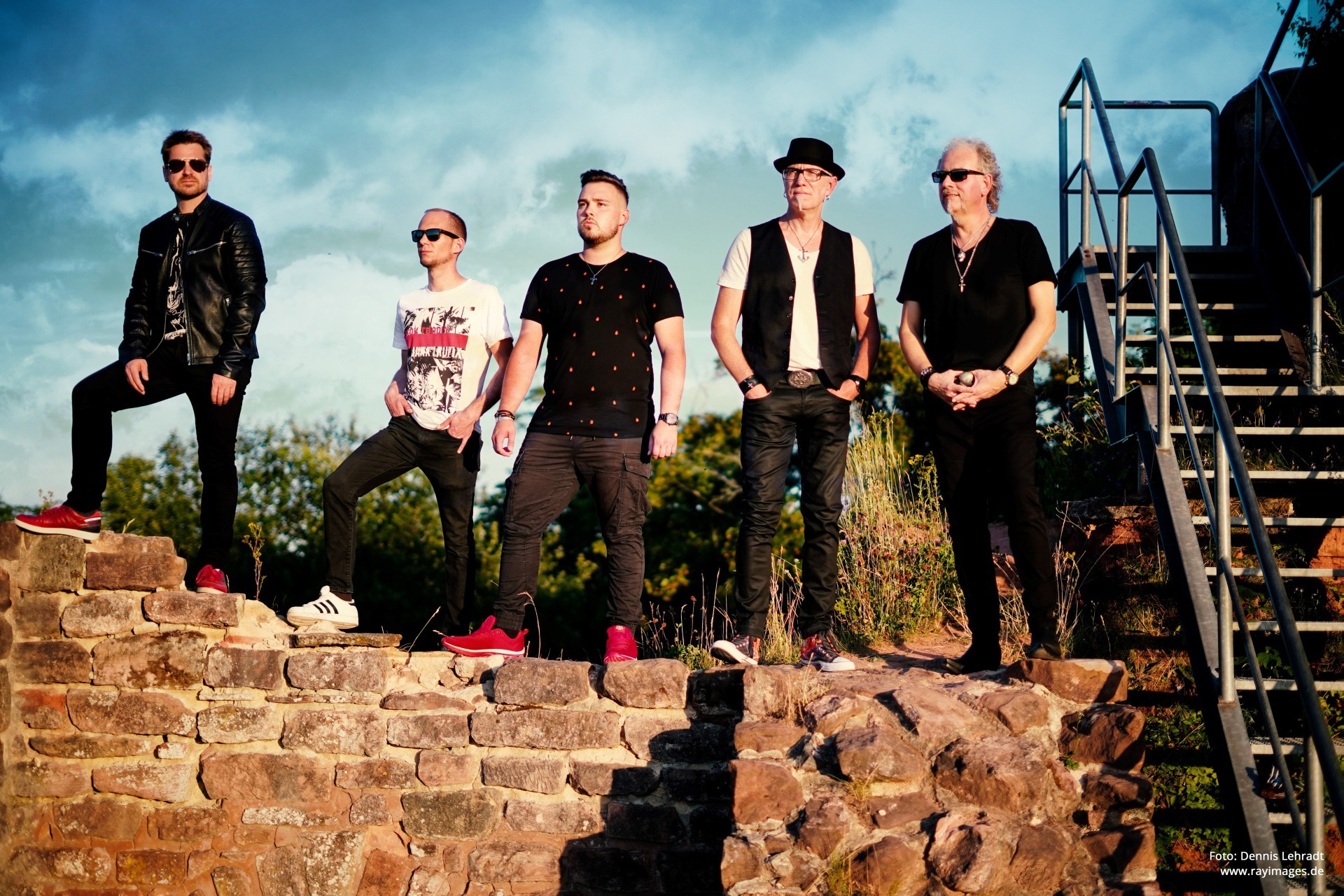 The photo shows the five band members standing on a wall and gazing into the distance.