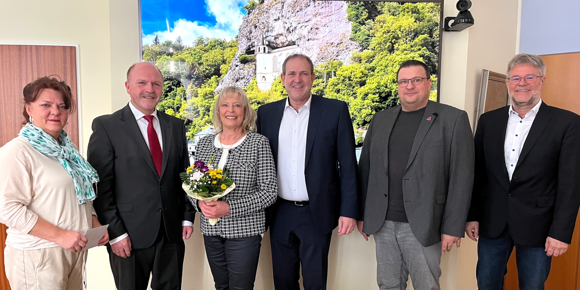 The photo shows the six participants in the farewell ceremony. Ms. Endres is holding a bouquet of flowers.