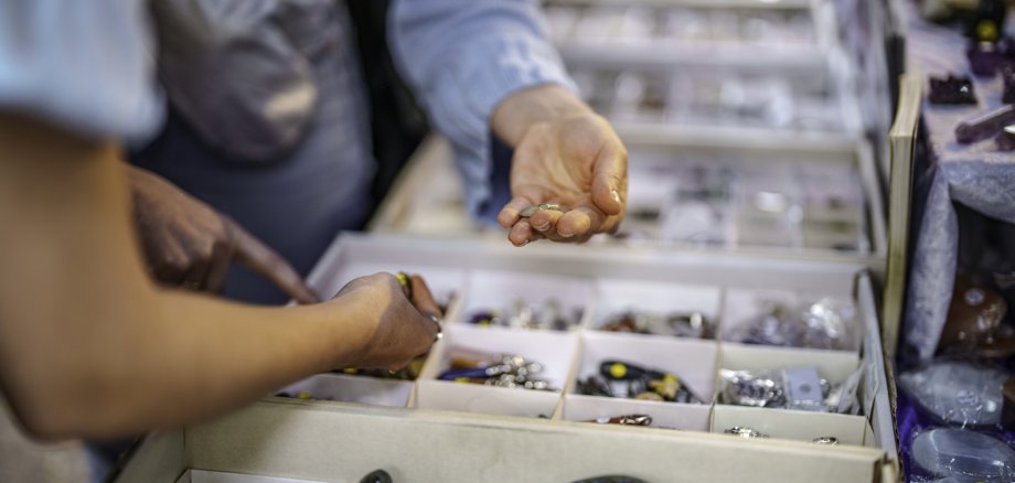 The photo shows a view of the display in a gemstone store. You can see the hands of two customers reaching for the stones.