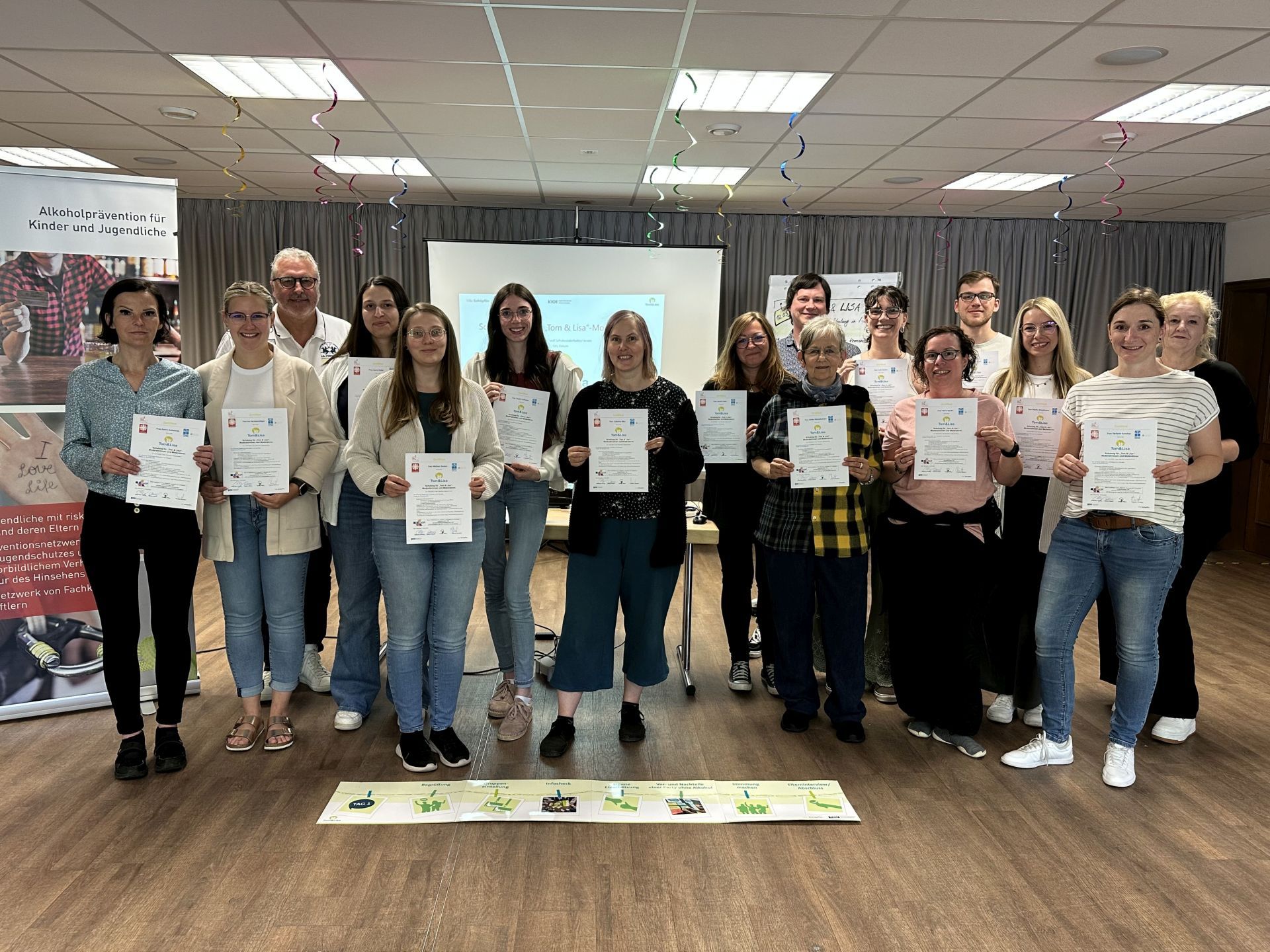 The photo shows the participants of the Tom & Lisa moderator training course with their certificate.