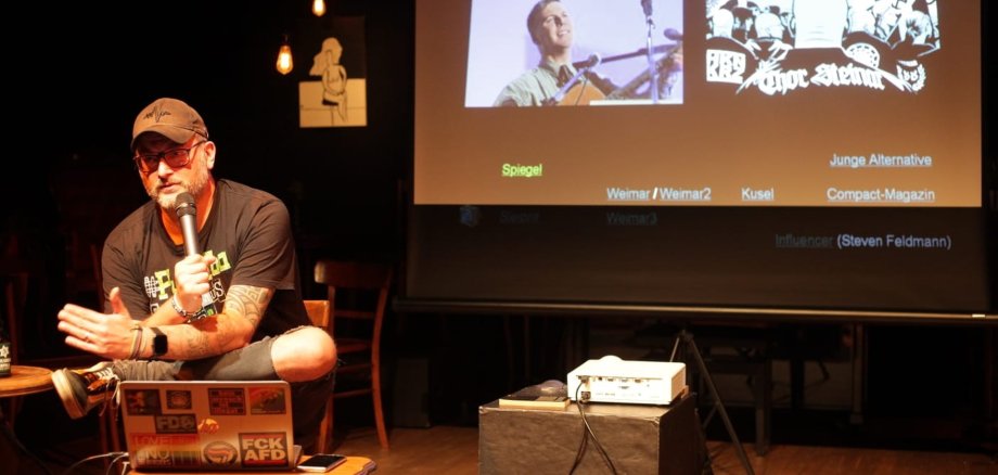 The photo shows Bastian Drumm during a presentation.