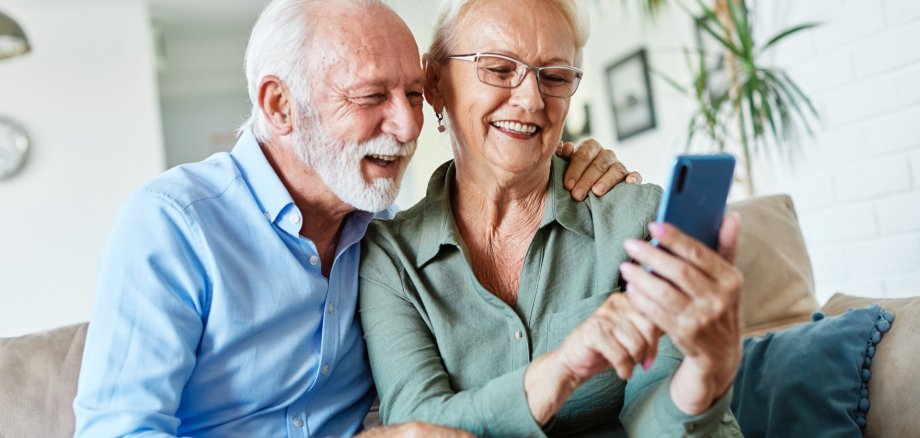 The photo shows two elderly people looking at a smartphone