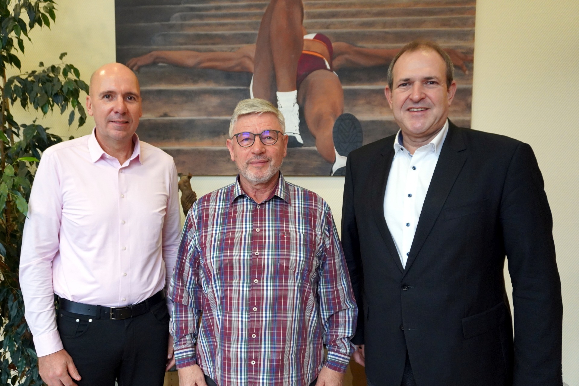 The photo shows the aforementioned people standing in front of a picture in the Lord Mayor's office and looking into the camera.