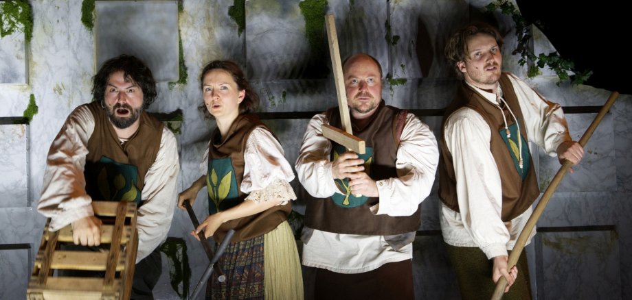 The photo shows the four actors in historical costumes.