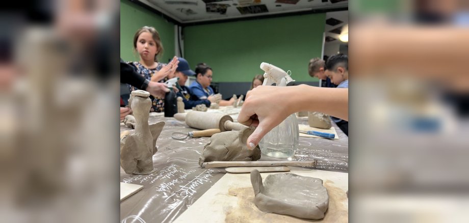 The photo shows children modeling with clay.