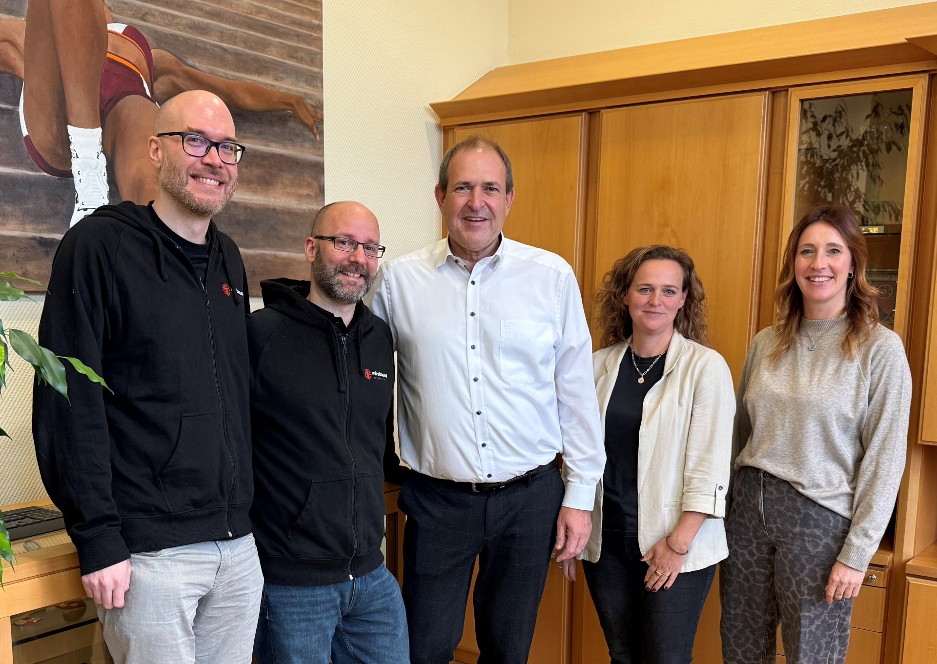 The photo shows the aforementioned people standing next to each other in Mayor Frühauf's office and looking into the camera.
