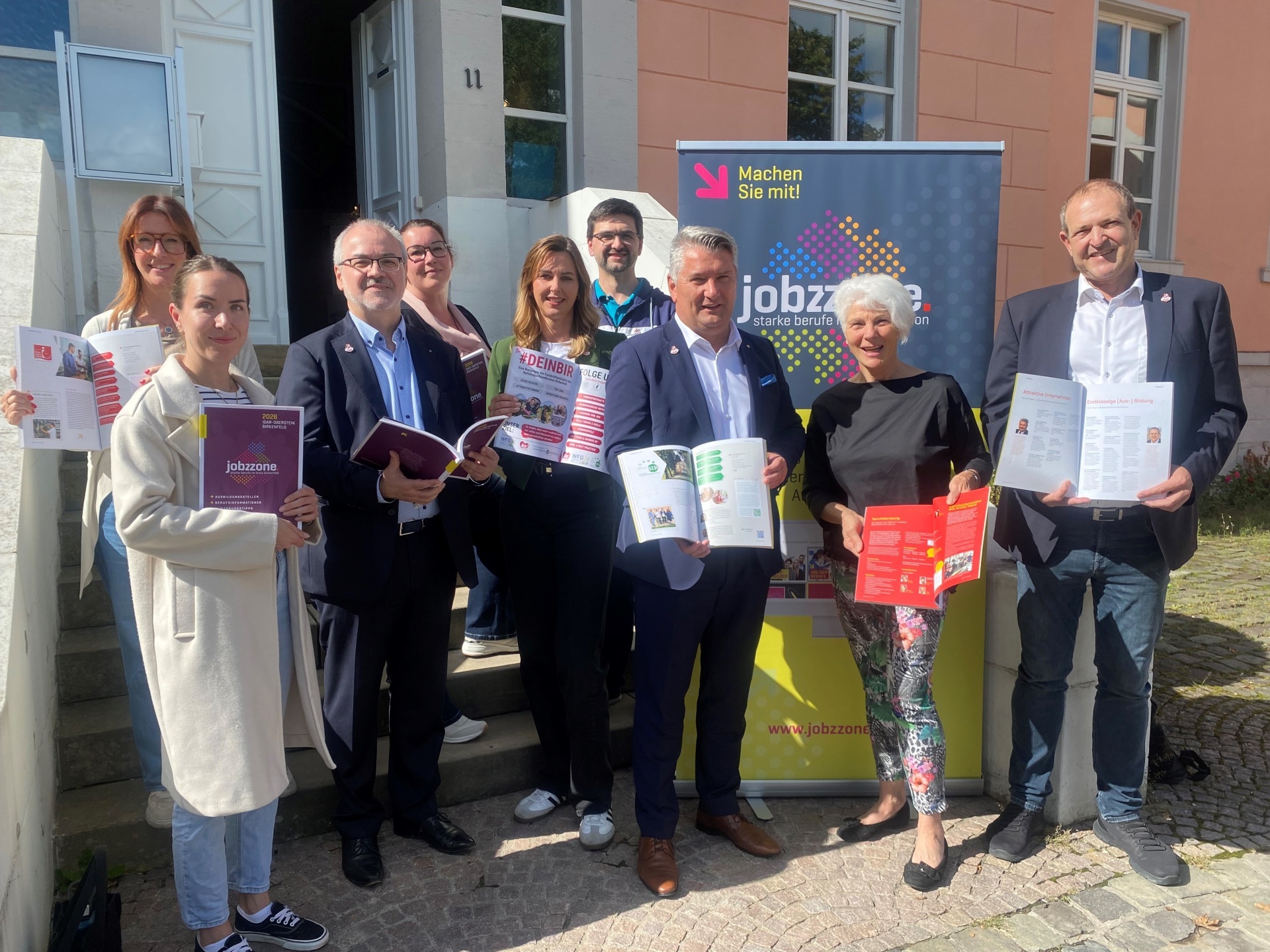 The photo shows the people in front of the Birkenfeld district administration. They are each holding a copy of the "jobzzone".