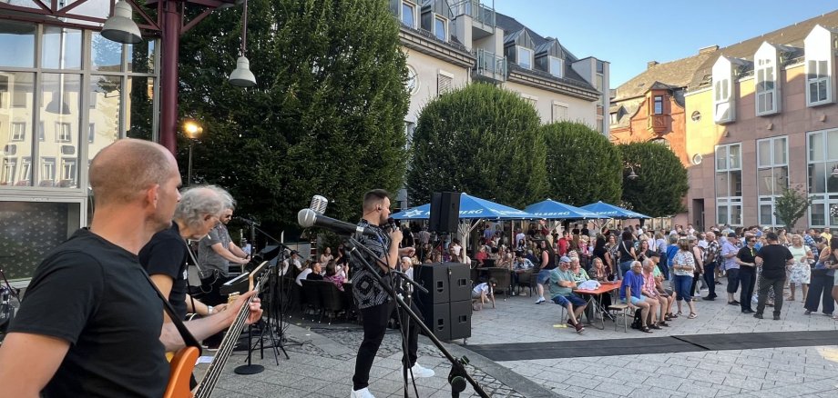 The photo shows a band at an after-work event in 2025 with lots of people on Schleiferplatz.