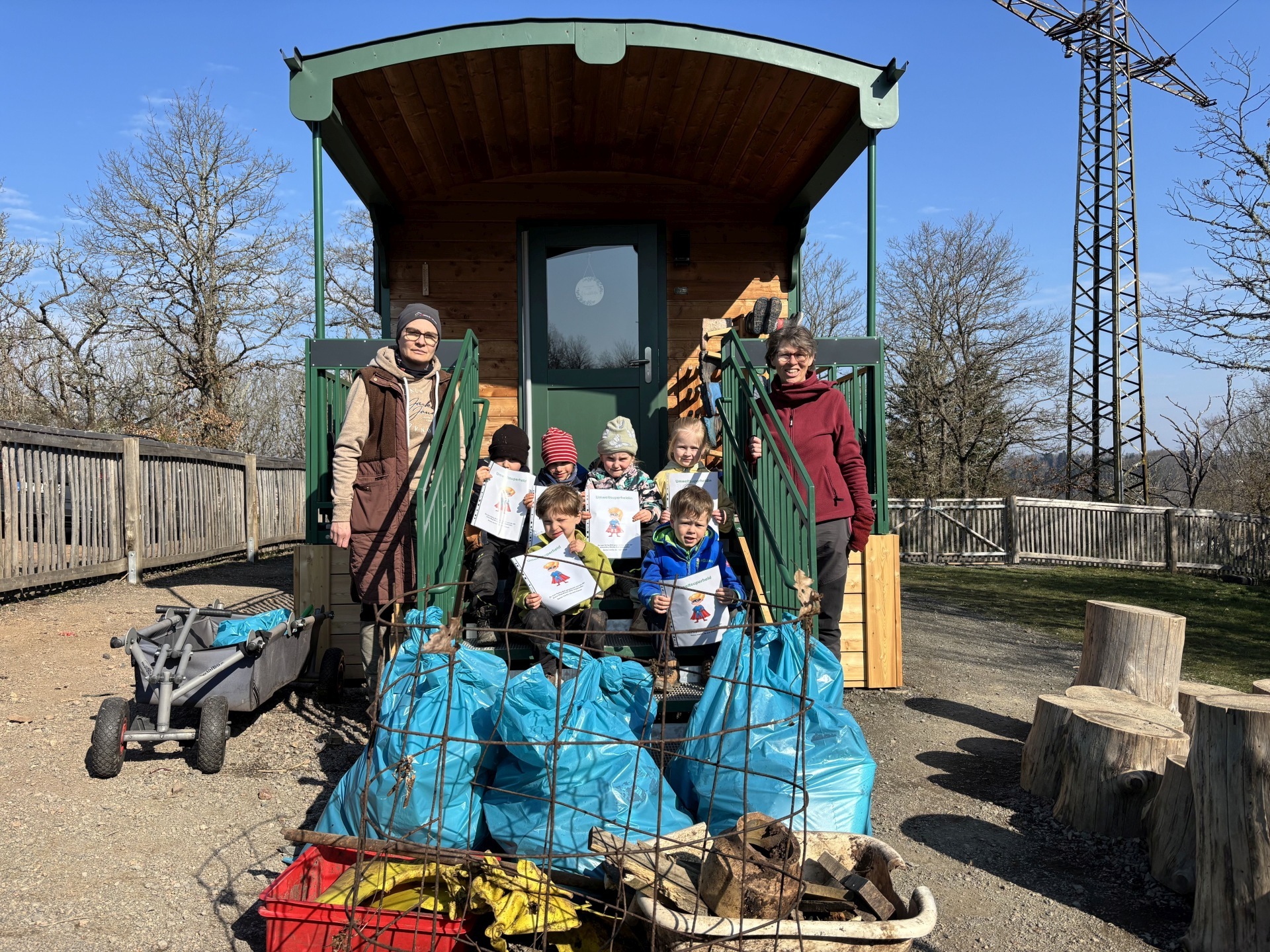 The photo shows the children and two teachers with the collected garbage.