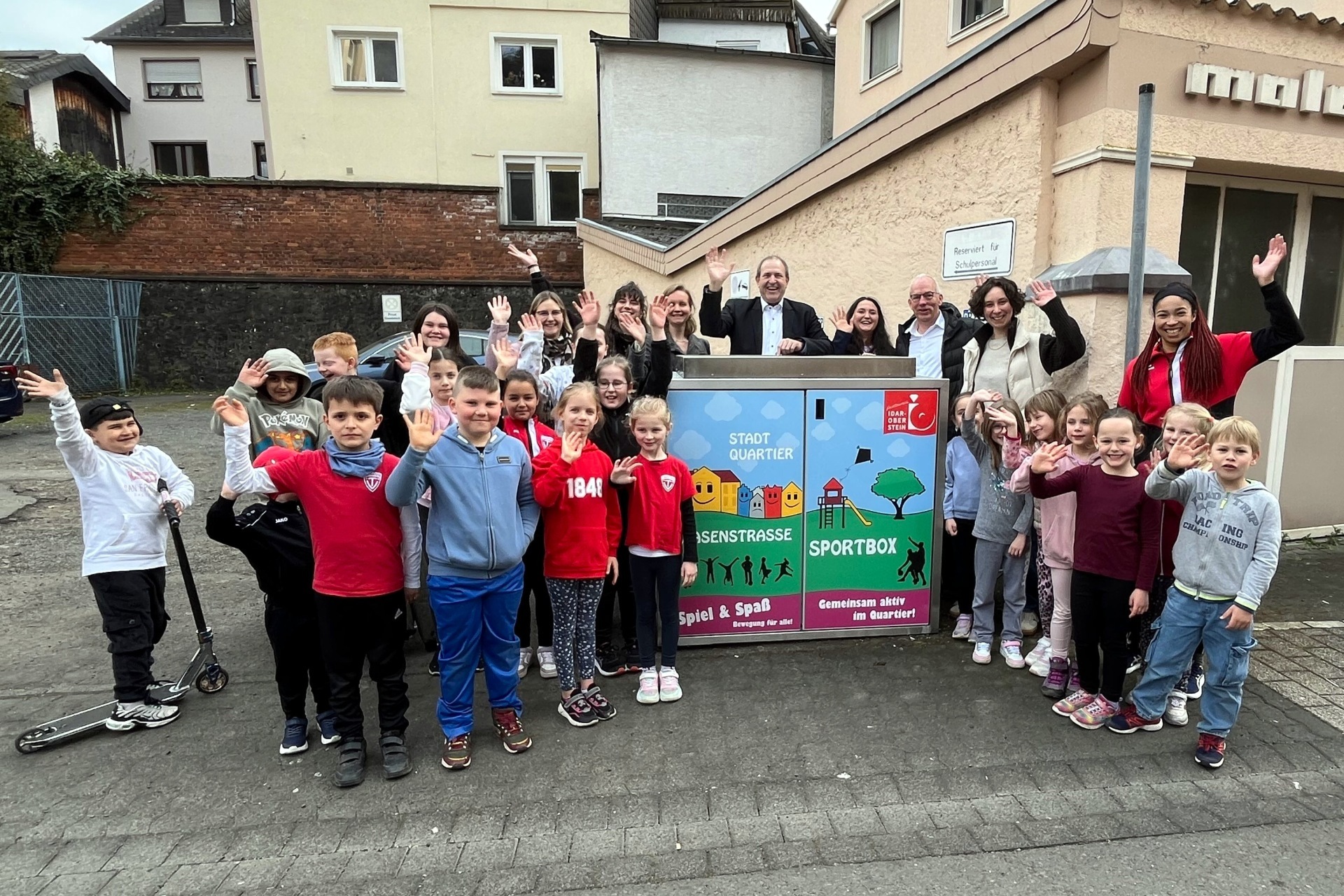 The photo shows many adults and children standing around the new sports box.