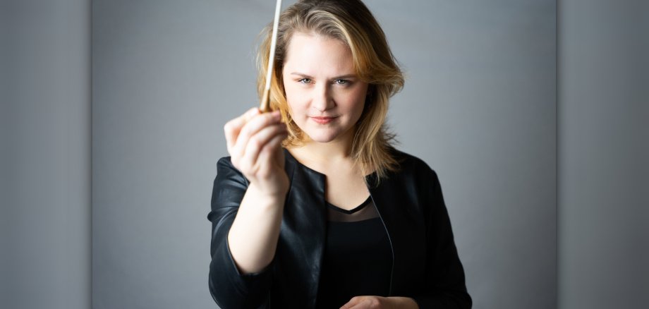 The picture shows a portrait photo of Raimonda Skabeikaité with conductor's baton.