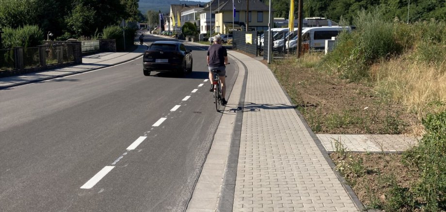The bike lane is already marked between the Weiherschleife and the Grimm Senior Living Center. The photo shows a driver and a cyclist on Tiefensteiner Straße.