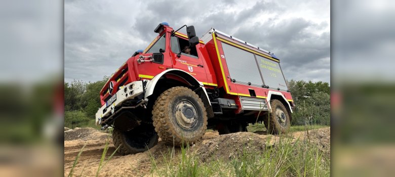 At the Nürburgring Offroad Park, members of the Idar-Oberstein Volunteer Fire Department practiced responding to emergencies in rough terrain using the TLF-3000 W. The photo shows the Unimog driving across the grounds.