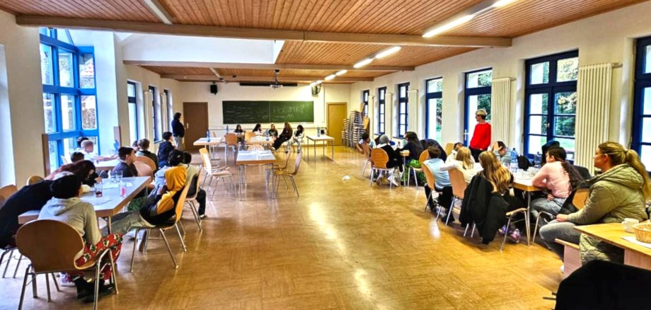 The photo shows a view of the training room, where a number of pupils are sitting at tables in front of a blackboard.