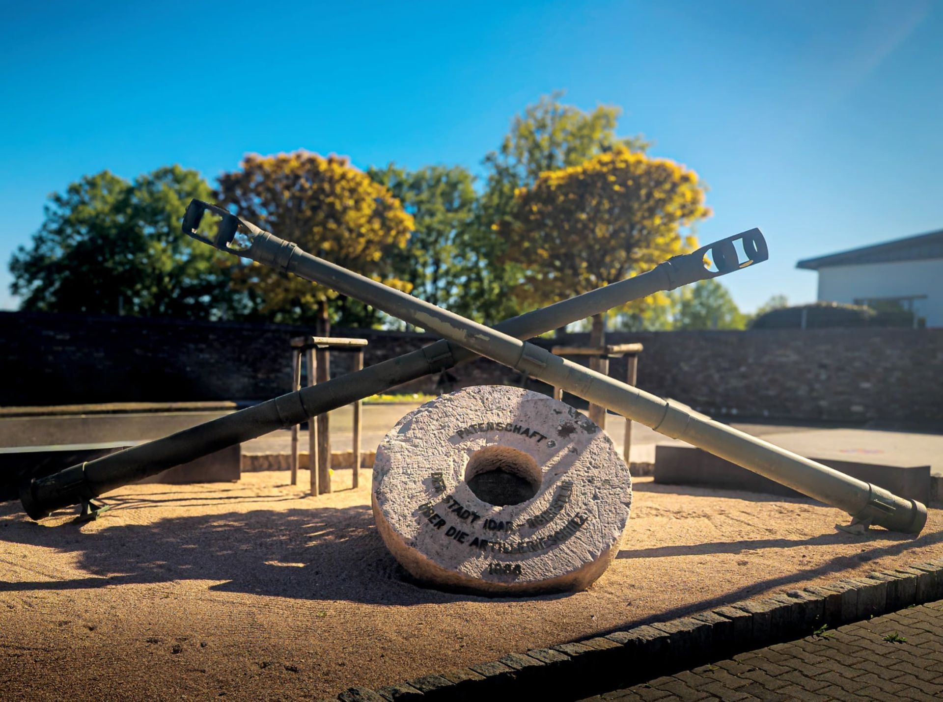 The monument shows a whetstone, a symbol of the art of gemstone cutting in Idar-Oberstein, and two crossed pipes as a symbol of artillery.